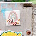 A colorful sticker with the text "You are magic" is attached to a weathered concrete surface.