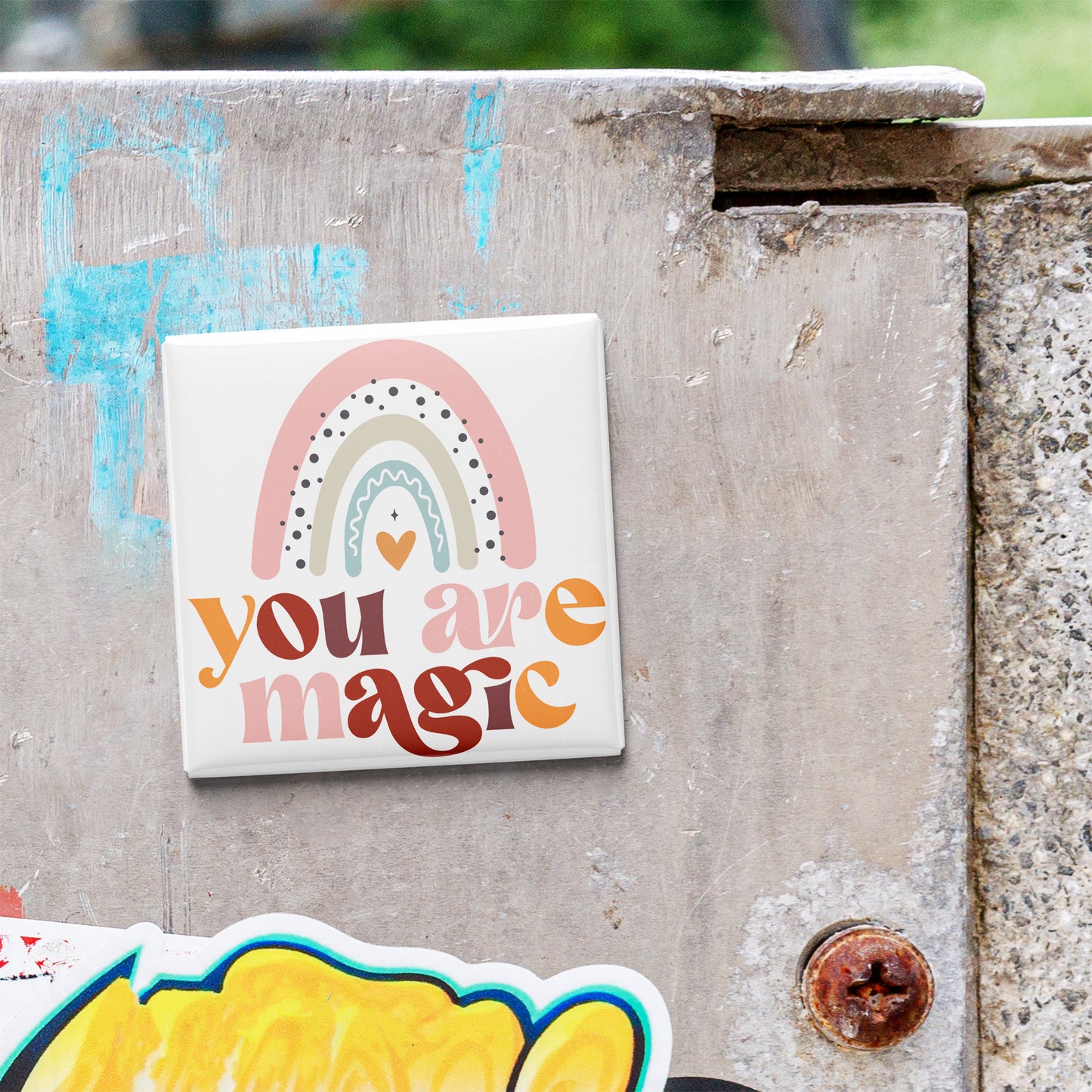 A colorful sticker with the text "You are magic" is attached to a weathered concrete surface.