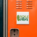 a vibrant orange wall with a sign that reads "Pickle Vibes" in a playful font.