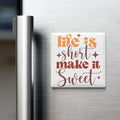 a refrigerator with a white magnet that says "Life is short, make it sweet" in a stylized font.