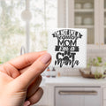 A hand holding a magnet with a humorous text that reads "I'M NOT LIKE A REGULAR MOM I'M A COT MAMA".