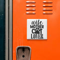 a sign with the text "wife mother cat lover" on an orange surface, with a small metal object below it.