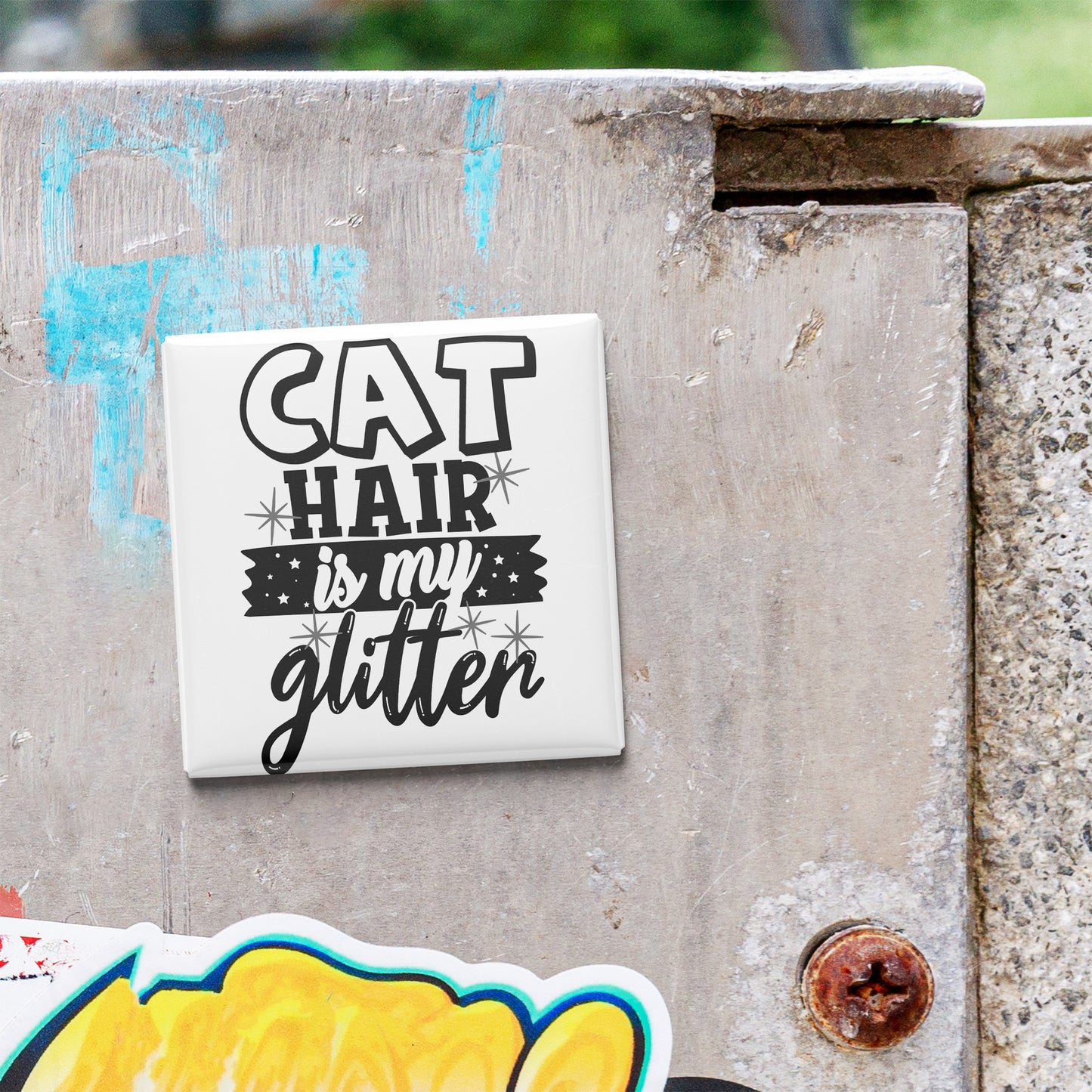 A sticker with the text "CAT HAIR is my glitter" is attached to a concrete surface.