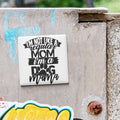 A sticker with the text "I'M NOT LIKE A REGULAR MOM I'M A DOG MAMA" is attached to a concrete wall.