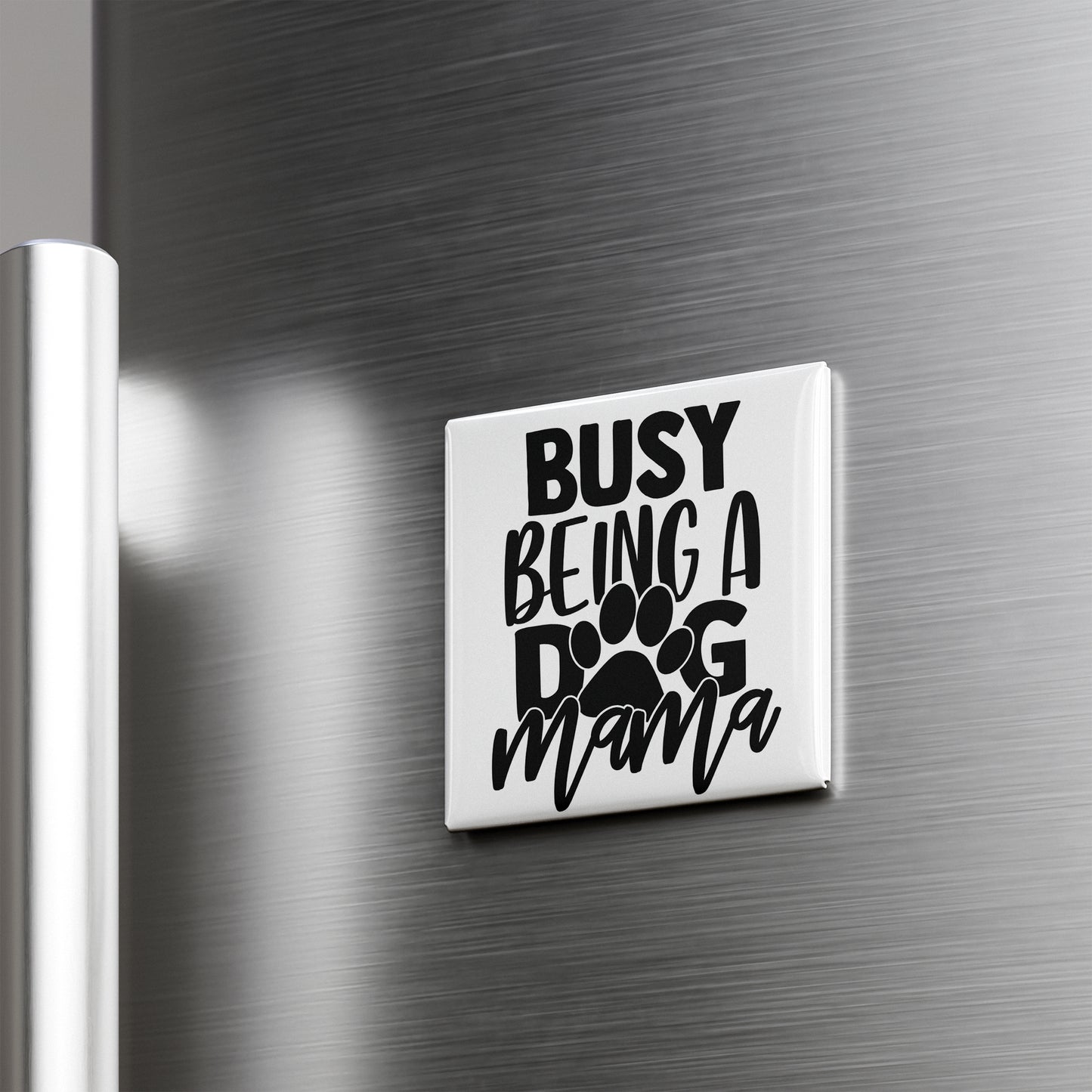 A white refrigerator magnet with the text "BUSY BEING A DOG MAMA" printed on it.