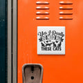 a sticker with the text "Yes, I Really Do Need All These Cats" on an orange surface, which appears to be a locker or a similar storage unit.