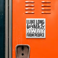 a sticker with the text "I LIKE LONG WALKS AWAY FROM PEOPLE" on an orange surface, which appears to be a locker or a similar storage unit.