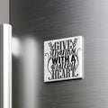 A white square magnet with a black text design that says "GIVE THANKS WITH A GRATEFUL HEART" attached to a metallic surface.