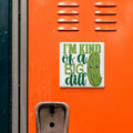 a sticker with a cartoon pickle and the text "I'm kind of a big dill" on an orange surface.