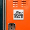 a close-up of an orange surface with a white sign that reads "home is where the dog is".