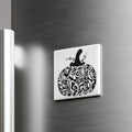 A decorative white square magnet with a black and white pumpkin design on it, mounted on a metallic surface.