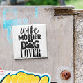 A white square magnet with the text "wife mother dog lover" is attached to a concrete wall.