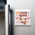 A white refrigerator door with a colorful magnet that says "mama you are magic" in a retro style.