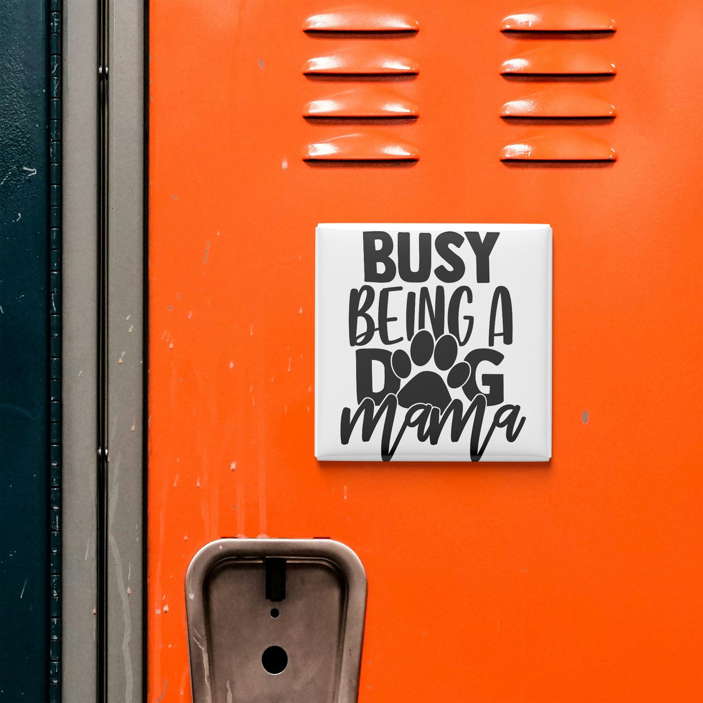 a sticker with the text "BUSY BEING A DOG MAMA" on an orange surface, which appears to be a locker or a similar storage unit.