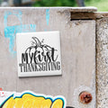 A white tile with the text "My first Thanksgiving" is attached to a concrete wall.