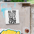 A white square magnet with the text "ALL YOU NEED IS LOVE AND A COOT" is attached to a concrete wall.