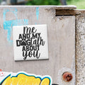 A white tile with the text "ME AND MY DOGTALK ABOUT YOU" is attached to a concrete surface.