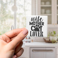 A hand holding a small white object with black text that says "wife mother cat lover".