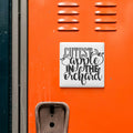 a vibrant orange wall with a white sign that reads "CUTEST APPLE IN THE ORCHARD" in a playful, artistic font.