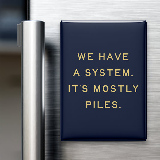 “We have a system. It's mostly piles.” quote magnet displayed on a refrigerator