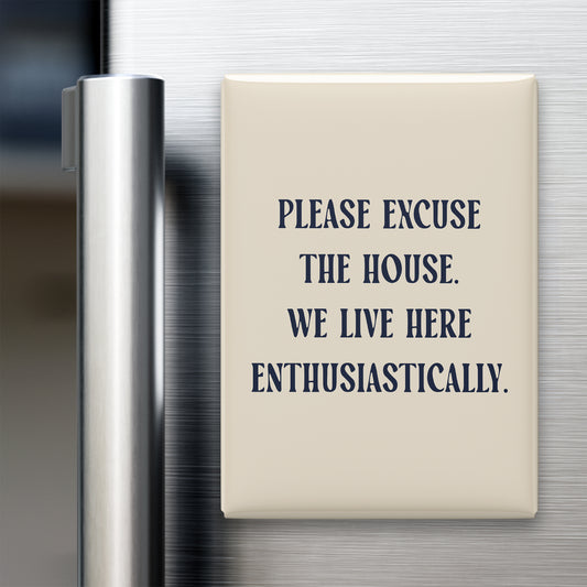 “Please excuse the house. We live here enthusiastically.” quote magnet displayed on a refrigerator