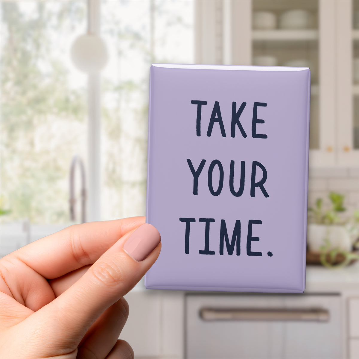 Hand holding the 2.5 × 3.5-inch “Take your time.” magnet in a kitchen