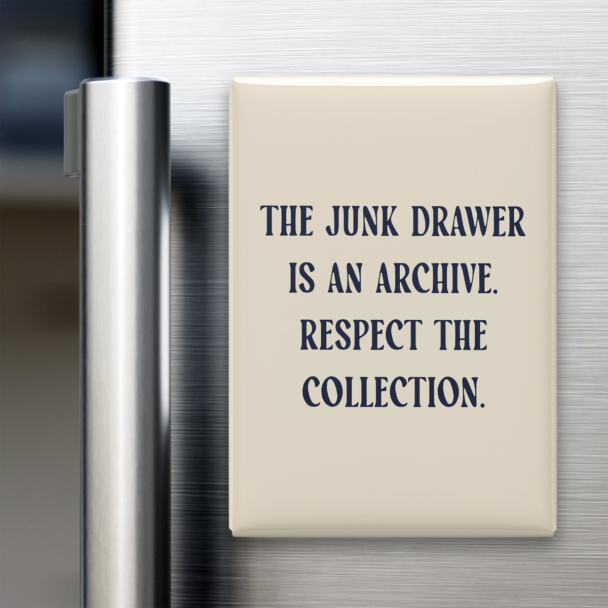 “The junk drawer is an archive. Respect the collection.” quote magnet displayed on a refrigerator
