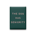 The Dog Has Seniority magnet in Blush lettering on a Spruce background, shown on white