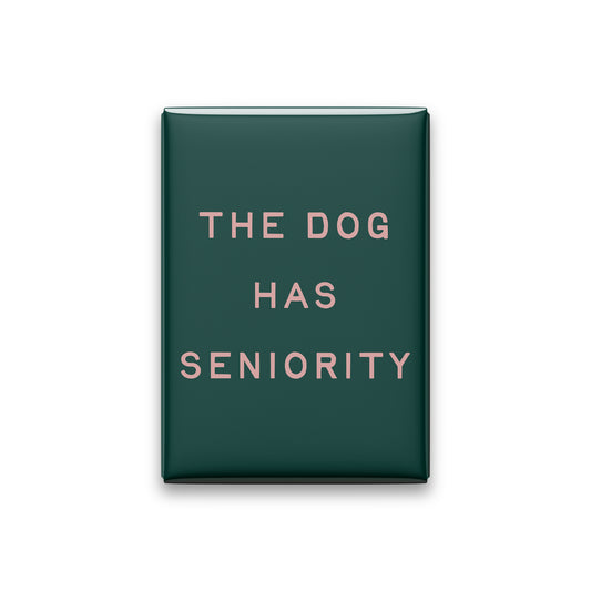 The Dog Has Seniority magnet in Blush lettering on a Spruce background, shown on white