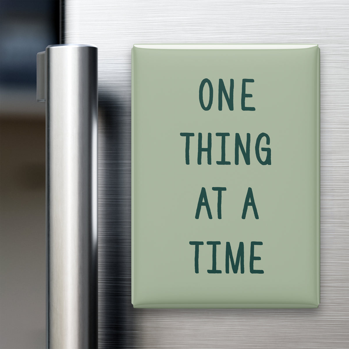 One Thing at a Time magnet in Spruce lettering on a Sage background, displayed on a refrigerator