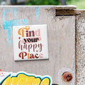 A sticker with the text "Find your happy place" is attached to a concrete wall.