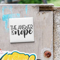 A white square magnet with the text "THE ANSWER IS NOPE" attached to a metal surface.
