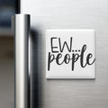 A white magnet with the text "EW... people" on it is attached to the side of a stainless steel refrigerator.