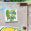 A sticker with a cartoon pickle and the text "I JUST REALLY LIKE PICKLES OK?" is attached to a concrete surface.