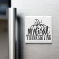 A refrigerator door with a white magnet that says "My first Thanksgiving" in a stylized font.