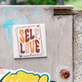 A sticker with the text "SELF LOVE" is attached to a concrete wall.