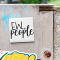 a white square magnet with the text "EW... people" written on it, which is attached to a weathered concrete surface.