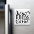 A refrigerator door with a white magnet that says "Thank GOD for October" in a stylized font.