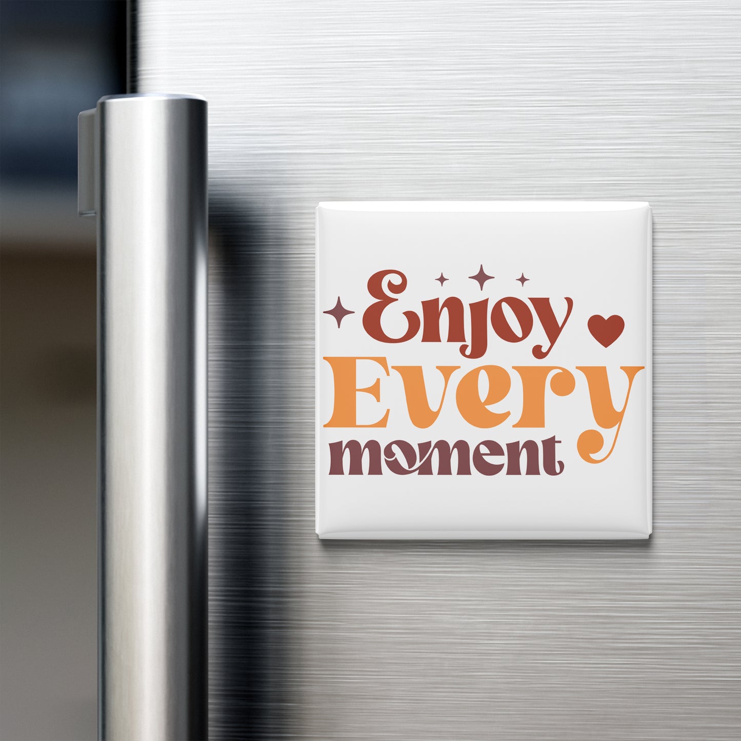 A white refrigerator magnet with the text "Enjoy Every moment" in orange and brown colors.