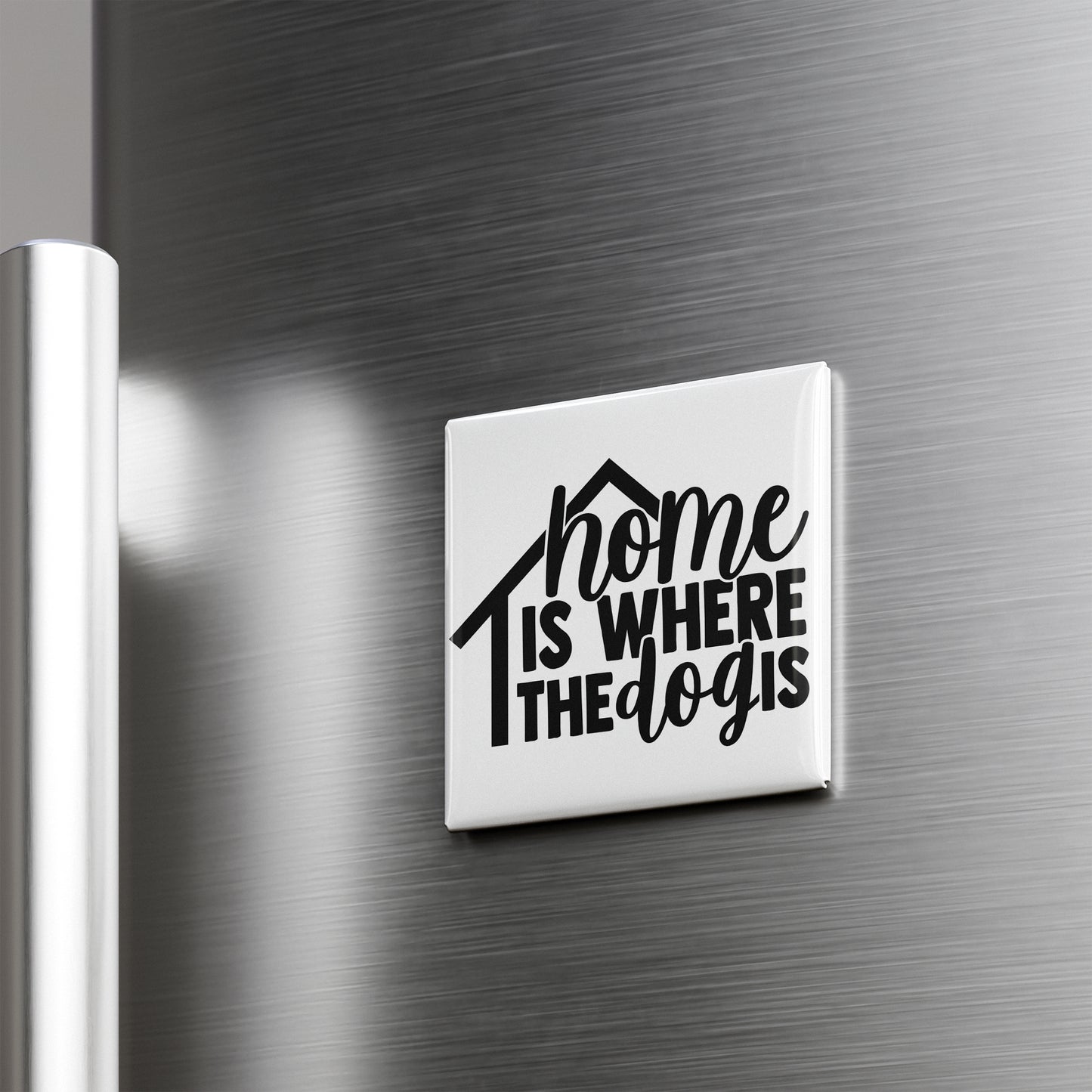 A white magnet with the text "home is where the dogs are" on it is attached to a metallic surface.