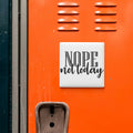 a bright orange surface with a white sign that says "NOPE not today".