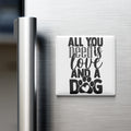 A white refrigerator magnet with the text "ALL YOU NEED IS LOVE AND A DOG" printed on it.