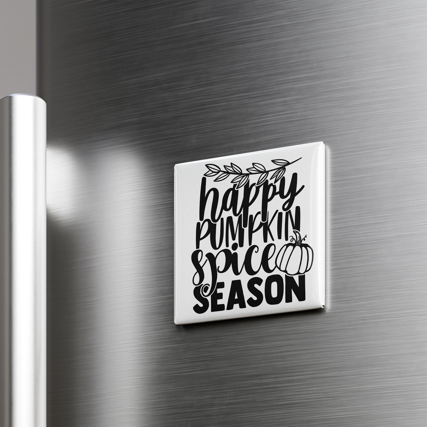 A white square magnet with black text that says "happy pumpkin spice season" is attached to a metallic surface.