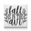the text "fall is in the air" in a stylized font, surrounded by decorative leaves.