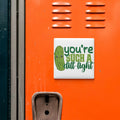 a sticker with a cartoon pickle and the text "you're such a drain light" on an orange surface.