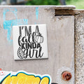 A white tile with black text that says "I'm a fall kinda girl" is attached to a concrete wall.