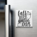 A refrigerator door with a magnet that says "fall days are fun days" along with an illustration of a pumpkin and an acorn.