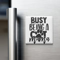 A white refrigerator magnet with the text "BUSY BEING A COT MAMA" printed on it.