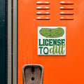 a sticker with a cartoon pickle and the text "License to dill" on an orange surface.