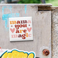 A sticker with the text "mama you are magic" is attached to a concrete wall.